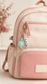 Charm attached to a backpack
Personalised pastel silicone backpack charm with custom name beads and flower detail attached to the zipper of a blush pink and beige school backpack.