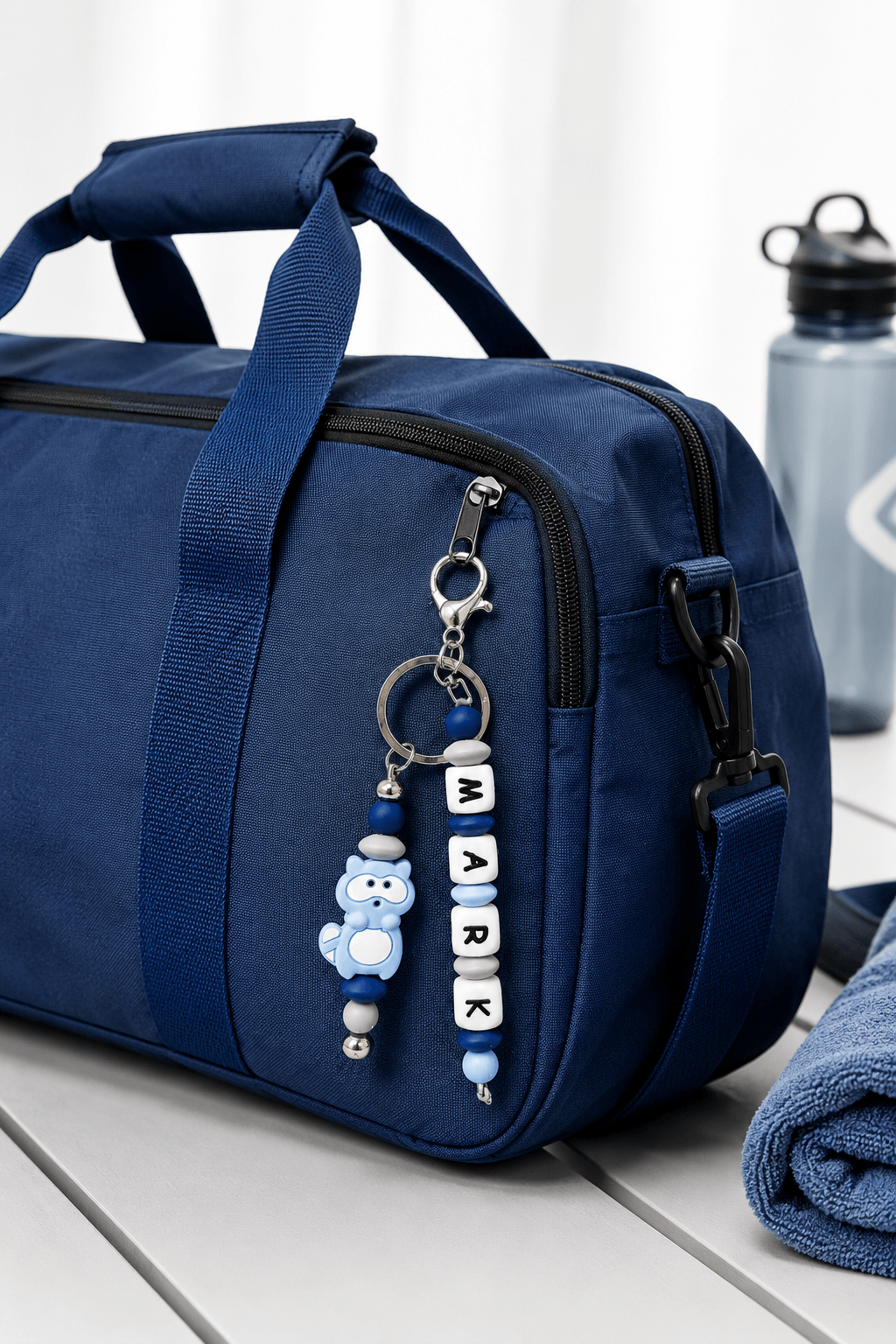 Personalised boys backpack charm with custom name, handmade silicone bead keychain in blue and black, clipped onto a school bag.