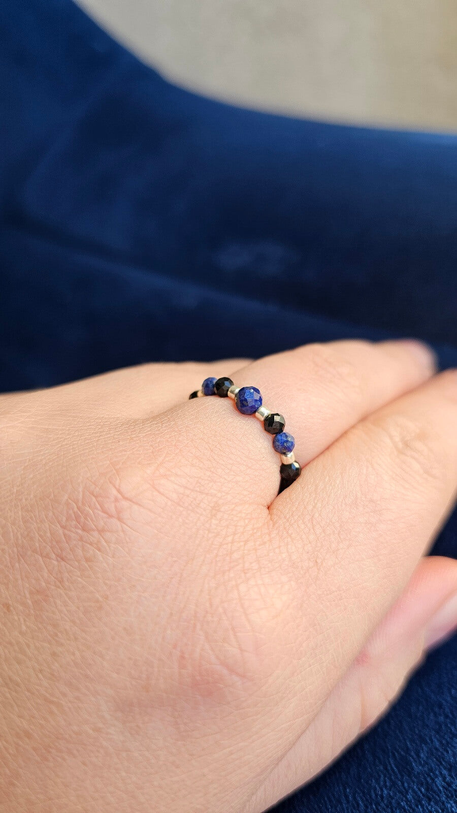 Three handmade elastic gemstone rings with Lapis Lazuli, Black Tourmaline and Moonstone beads, featuring gold and silver accents on a minimalist background.