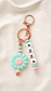 Product on linen background
Personalised silicone bag charm with custom name letter beads, pastel pink and mint beads, rose-gold hardware and daisy flower charm displayed on a soft neutral linen background.