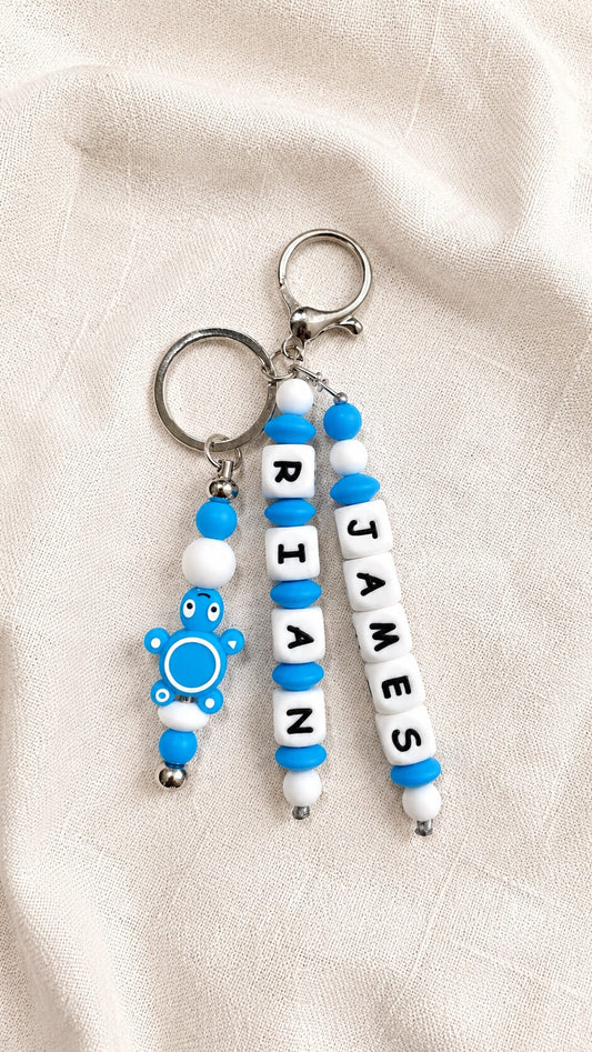 Personalized blue and white backpack and bag charm with a child’s name and cute turtle charm, handmade keychain for school bags and backpacks.
