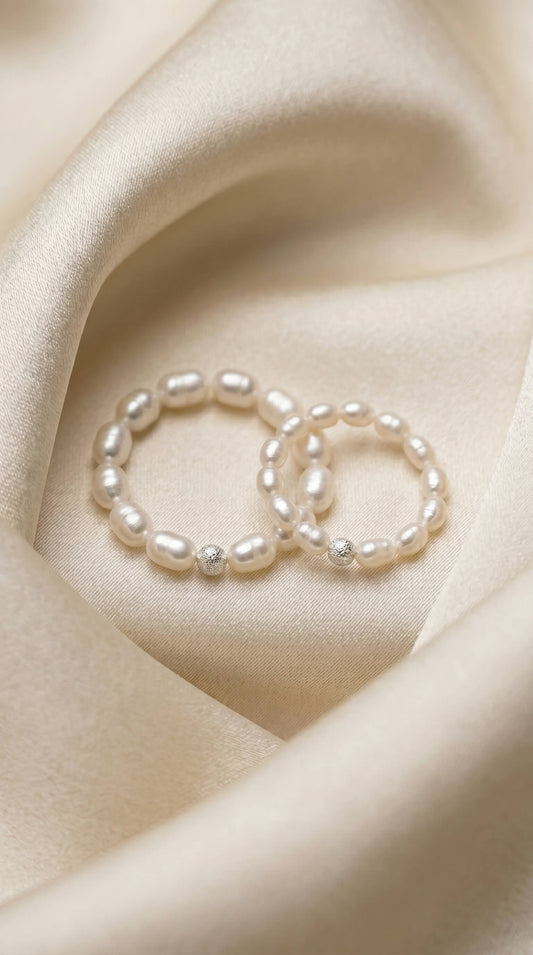 Macro photograph of natural freshwater rice pearls with a deep satin lustre, threaded on a durable stretch cord next to a diamond-cut sterling silver bead.