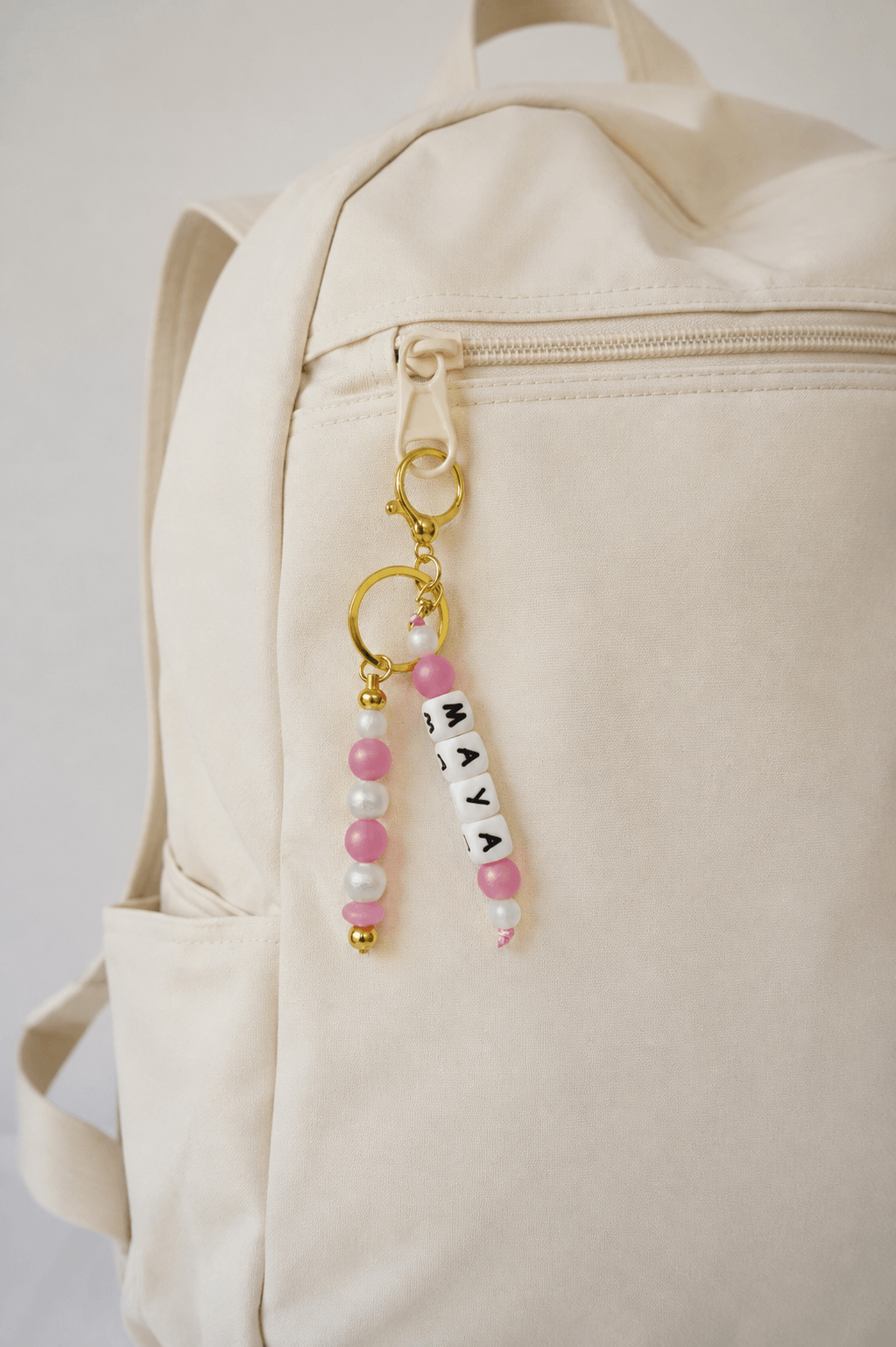 Handmade silicone bag charm with pearl and blush pink beads, displayed beautifully on natural beige linen.