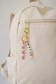 Handmade silicone bag charm with pearl and blush pink beads, displayed beautifully on natural beige linen.
