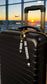 Personalised black and white silicone bead luggage tag with gold-tone hardware attached to a suitcase, custom family name travel accessory.
