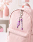 Personalised silicone backpack charm with custom name beads, pastel colours and flower detail, handmade in Ireland and attached to a school bag.
