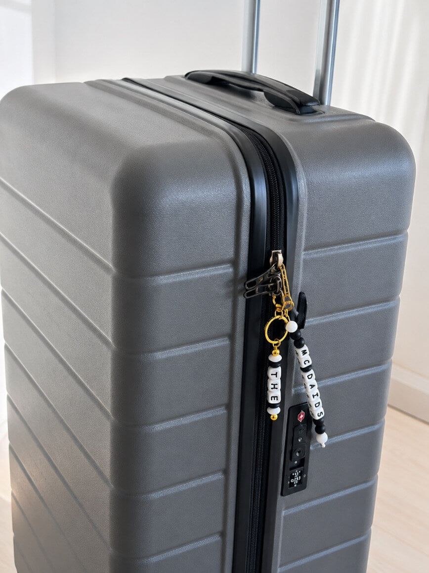 Personalised surname luggage tag on a black backpack and travel bag, stylish custom accessory for adults travelling through an airport.
