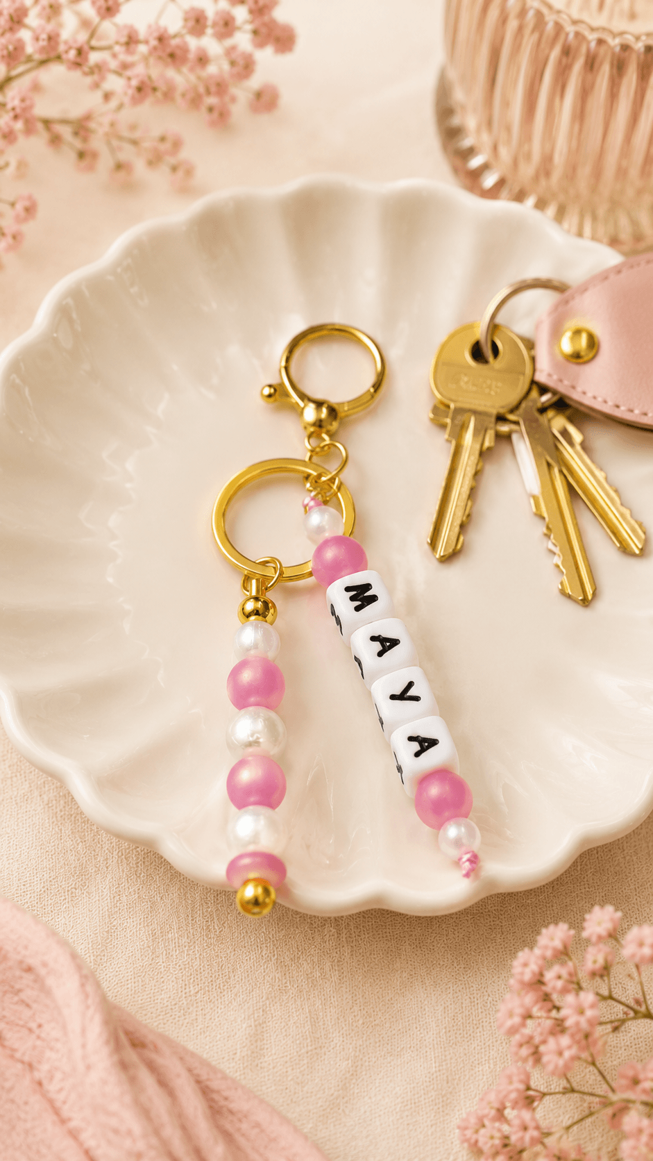 Elegant silicone bag charm with pearl and soft pink beads and gold-tone hardware on a soft cream background.