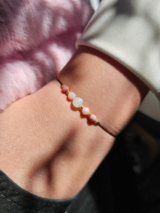 Handmade lucky bracelet with natural Moonstone, Pink Opal, and Rhodonite stones on a delicate pink nylon cord, featuring sterling silver stoppers and sparkling TOHO glass beads. Adjustable, stylish, perfect for love, emotional healing, protection, and spiritual growth. Ideal gift for her.

