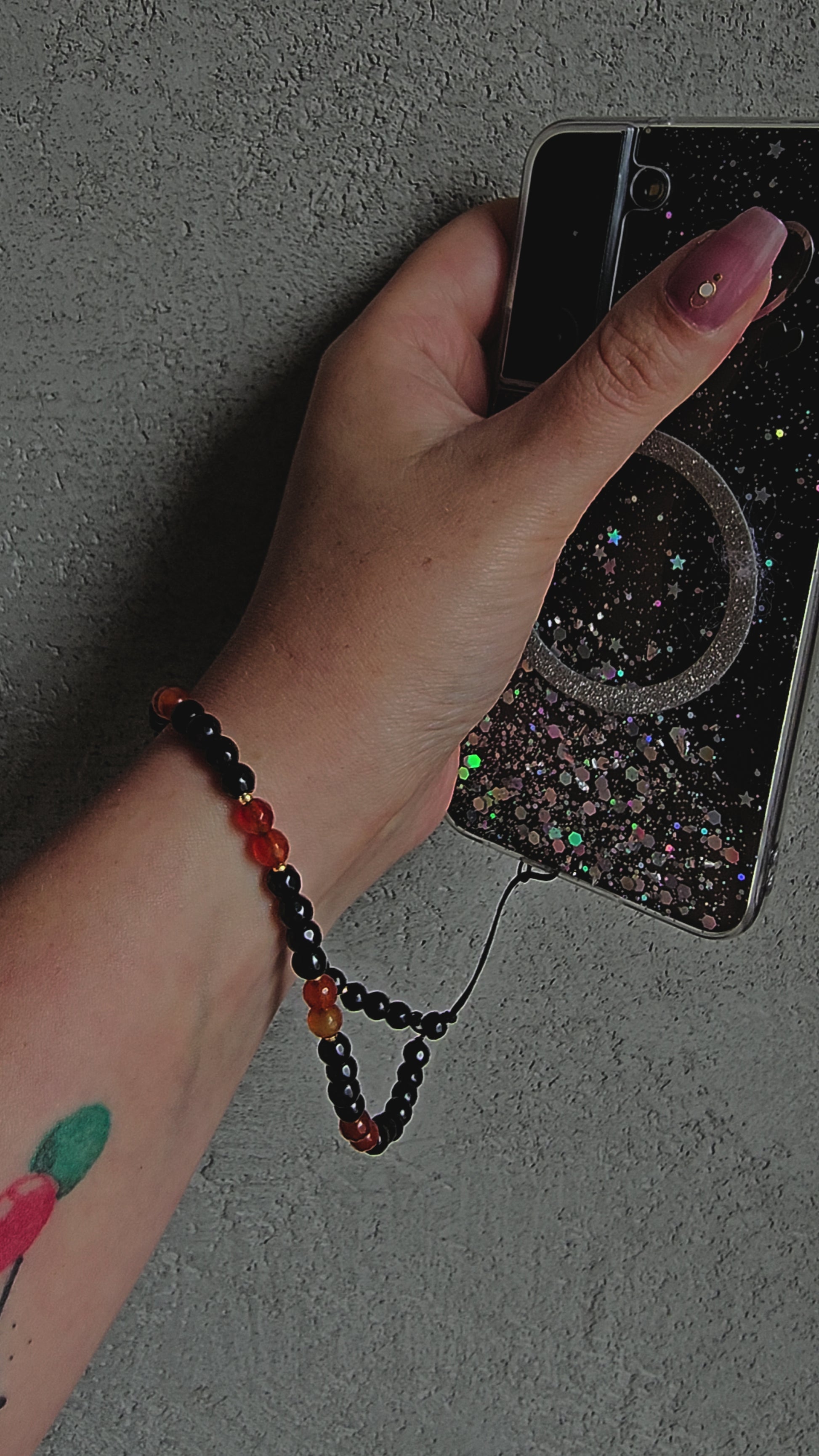 Handmade crystal phone charm with black onyx and carnelian beads, gold accents and cord – protective, grounding and energising accessory.