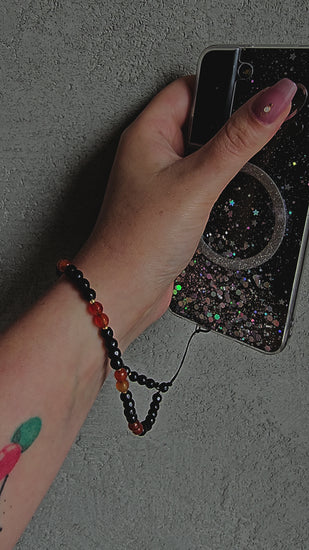 Handmade crystal phone charm with black onyx and carnelian beads, gold accents and cord – protective, grounding and energising accessory.
