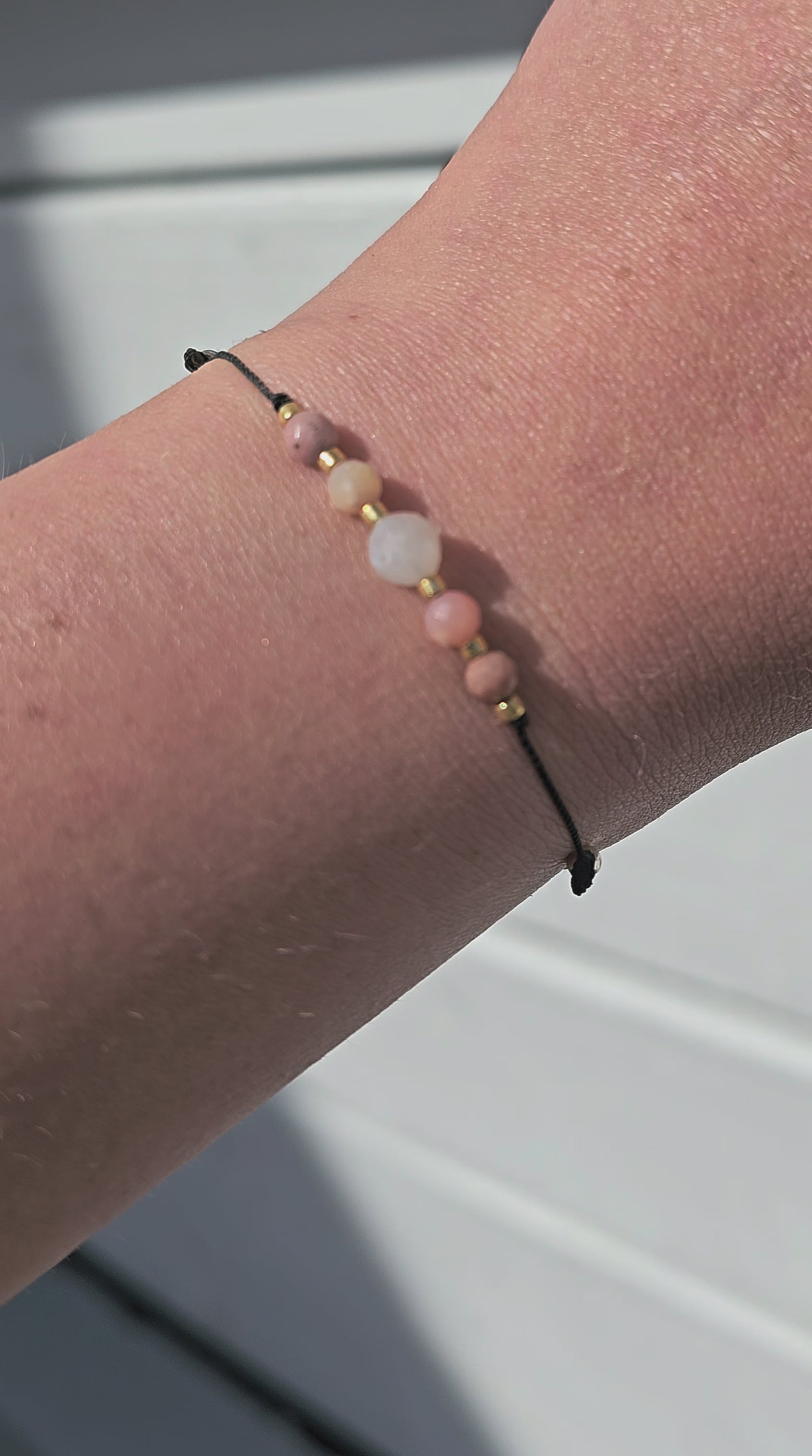 Handmade lucky bracelet with natural Moonstone, Pink Opal, and Rhodonite stones on a delicate pink nylon cord, featuring sterling silver stoppers and sparkling TOHO glass beads. Adjustable, stylish, perfect for love, emotional healing, protection, and spiritual growth. Ideal gift for her.
